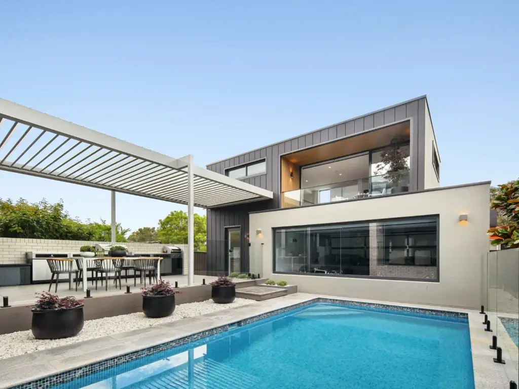 A Louvretec roof installation by a pool and contemporary living area, an example of the outdoor roof shade structures that can be achieved for you by Douglas Innovation